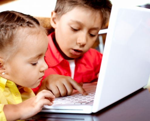 Portrait of cute children typing on laptop